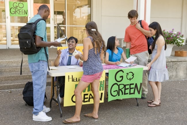 Students standing a table with a sign reading 'Go Green'