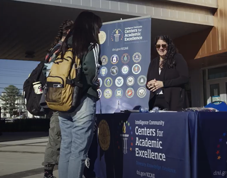 A woman stands behind the Centers for Academic Excellence table