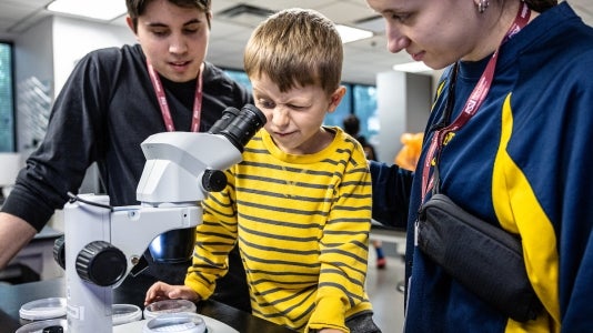 Five-year-old Adin Lubovac, studies tiny bugs in a biology lab with his sister Ena Mesic and her boyfriend Adam Doherty at ASU Open Door on Saturday, Feb. 3, 2024, on the downtown Phoenix campus. Photo by Charlie Leight/ASU News