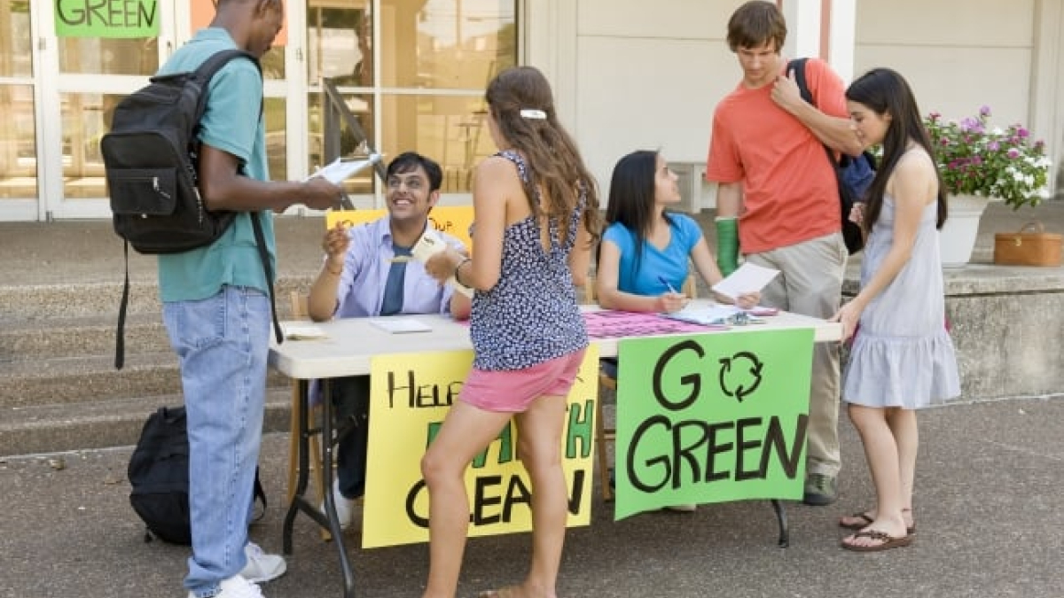 Students standing a table with a sign reading 'Go Green'