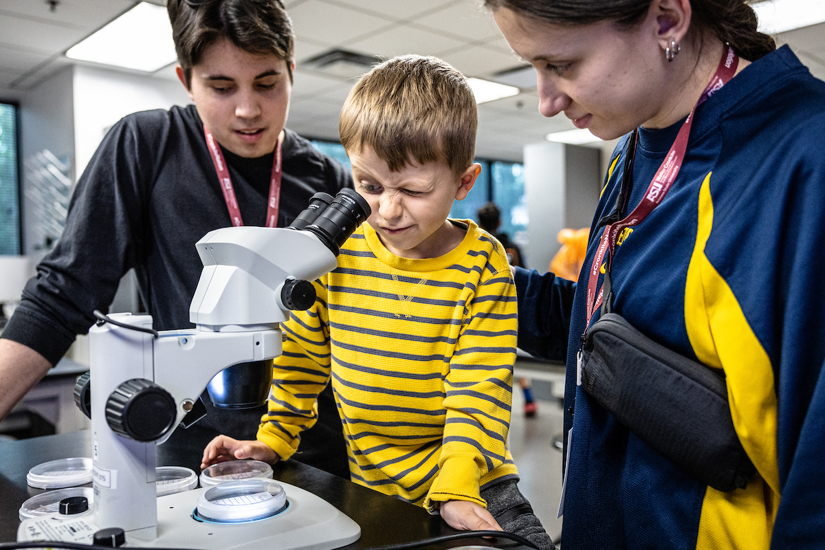 Five-year-old Adin Lubovac, studies tiny bugs in a biology lab with his sister Ena Mesic and her boyfriend Adam Doherty at ASU Open Door on Saturday, Feb. 3, 2024, on the downtown Phoenix campus. Photo by Charlie Leight/ASU News